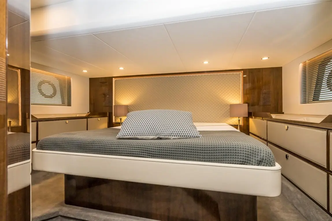 Luxurious boat bedroom featuring a large bed, decorative pillows, ambient lighting, and modern furnishings.